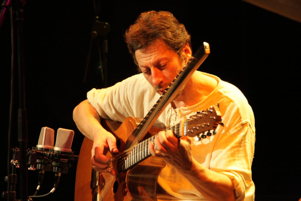 Michel Gentils jouant d'une guitare à deux manches.